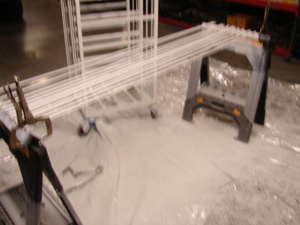 white pipes laid out on a tarp, supported by sawhorses and a cart