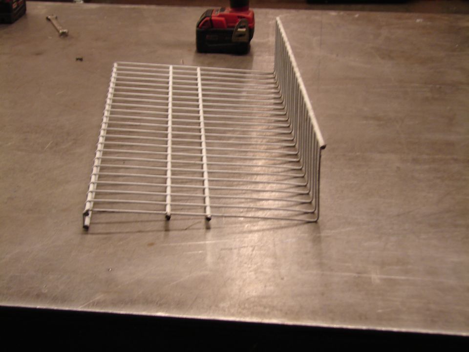 Wire rack on a workbench with a drill and wrench in the background