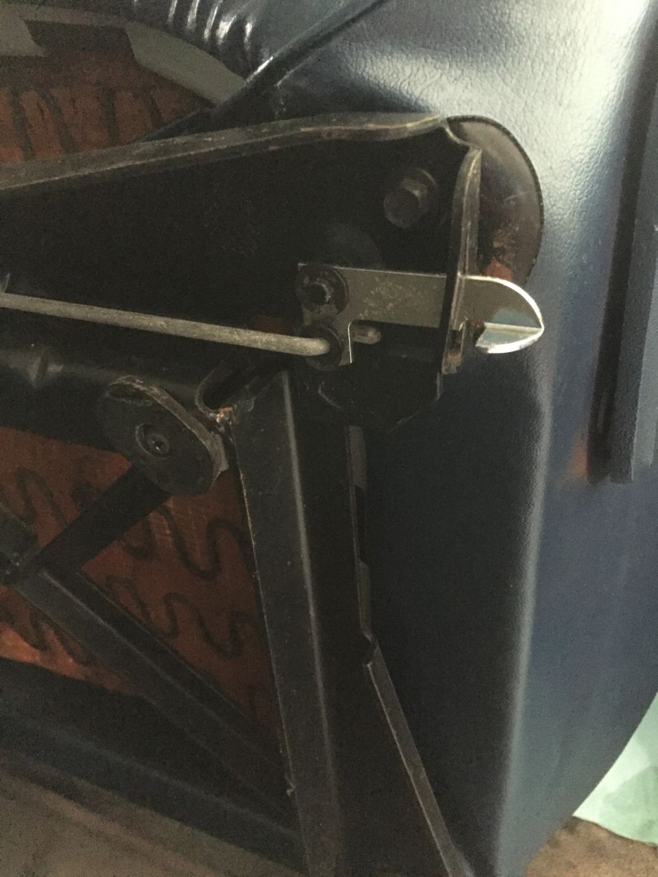 Underside of a blue vinyl seat showing black seat track hardware, adjustment rod, and latch bracket