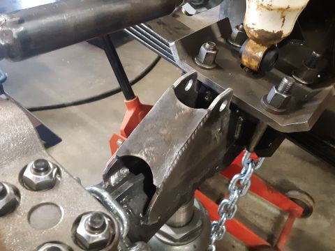 1985 Toyota Hilux - Close-up view of vehicle suspension components, including a metal bracket and chain, supported by jack stands.