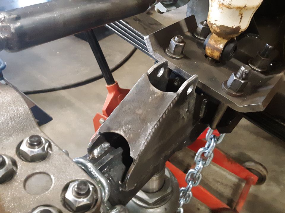 Metal bracket and chain attached to vehicle suspension with jack stands