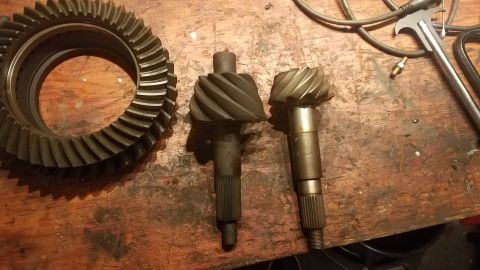 1985 Ford Bronco - Differential ring gear and two pinion shafts, one marked '4.10', laid out on a workbench.