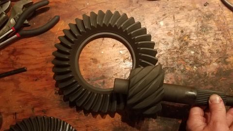 1985 Ford Bronco - Differential ring and pinion gears are laid out on a wooden surface, possibly for repair or replacement.