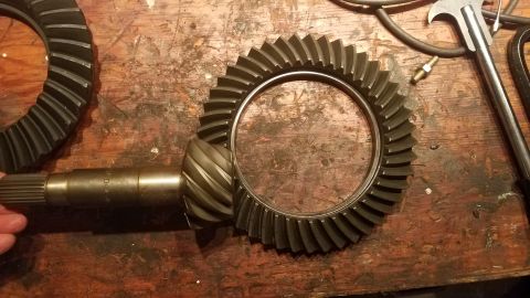 1985 Ford Bronco - Differential ring gear and pinion gear set on a wooden workbench, with tools in the background.