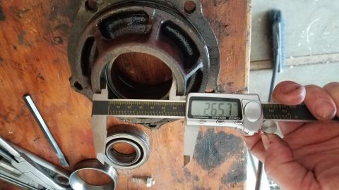 1985 Ford Bronco - A differential housing and bearing are measured with digital calipers, indicating a reading of 26.57.