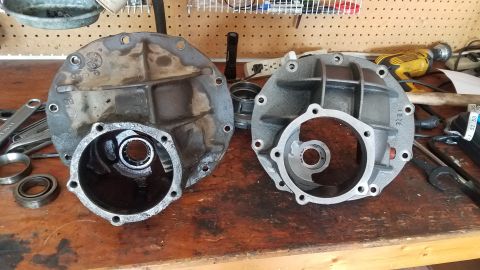 1985 Ford Bronco - Two differential housings are shown on a wooden workbench. The housing on the left appears older and dirtier, while the housing on the righ…