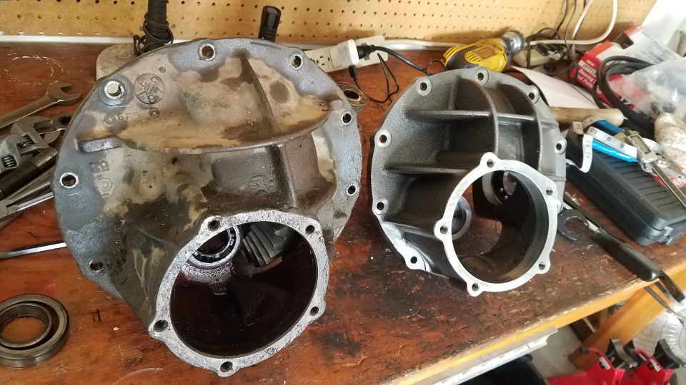 Two differential housings on a workbench with tools in the background.