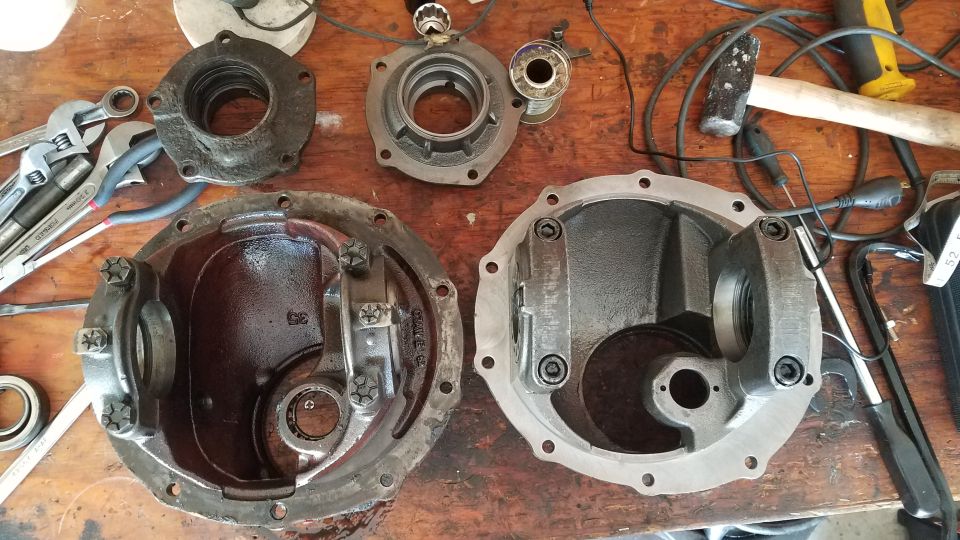 Two differential housings and tools on a wooden workbench.