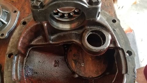 1985 Ford Bronco - A close-up, overhead view of an open differential housing with a bearing assembly visible inside. The housing is dark red and appears to be…