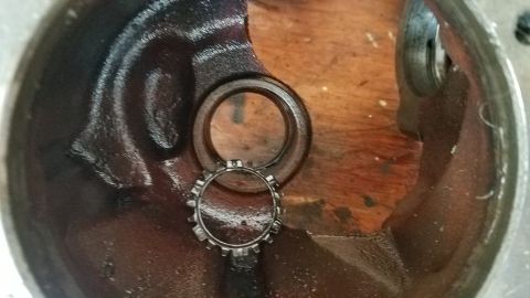 1985 Ford Bronco - A close-up view shows a metal ring with gear-like teeth inside a greasy, dark metal housing. Another larger metal ring is visible above the…