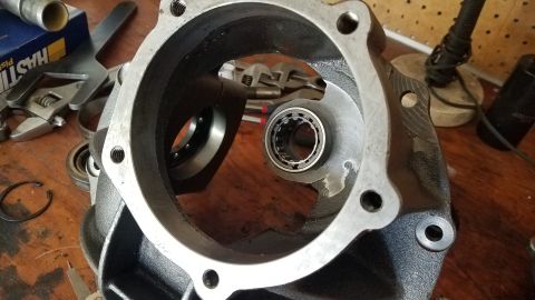 1985 Ford Bronco - A close-up view of a disassembled differential housing with bearings and tools on a wooden workbench.