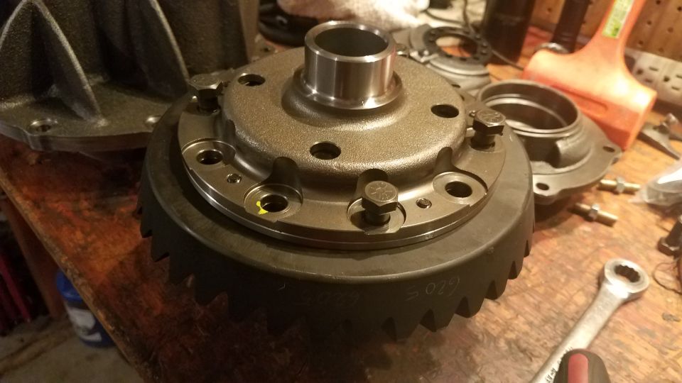 Differential housing and ring gear with "5029" visible, on a workbench with tools.