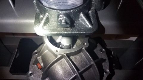 1985 Ford Bronco - A close-up view of a differential housing with a driveshaft entering it. The housing is cast iron and bolted to a larger metallic component…