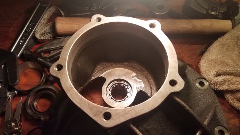 1985 Ford Bronco - A close-up view of a differential housing with a bearing installed, surrounded by various tools including a wrench, pliers, and a measuring…