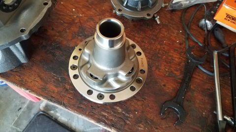 1985 Ford Bronco - A differential housing sits on a wooden workbench next to a wrench and other automotive parts.