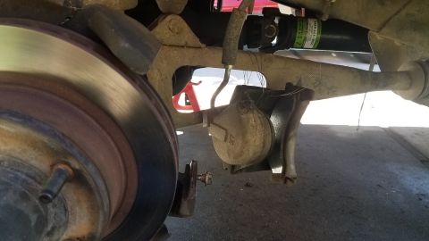 1985 Ford Bronco - This is a close-up view of the rear brake assembly of a vehicle, showing the brake rotor, caliper, and suspension components. A driveshaft…