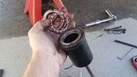 1985 Ford Bronco - A hand holds a black component with a red accent, suggesting it is a part of a larger mechanism or tool.