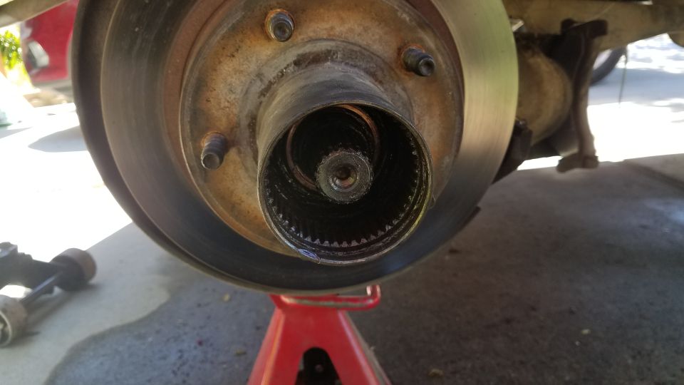 Close-up of a vehicle's wheel hub and brake rotor assembly, supported by a red jack stand