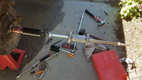 1985 Ford Bronco - Tools laid out on the ground for a wheel hub repair, including a slide hammer puller.