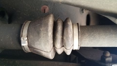 1985 Ford Bronco - A close-up view of a CV axle boot on a vehicle's undercarriage. The rubber boot is pleated and secured with metal clamps.