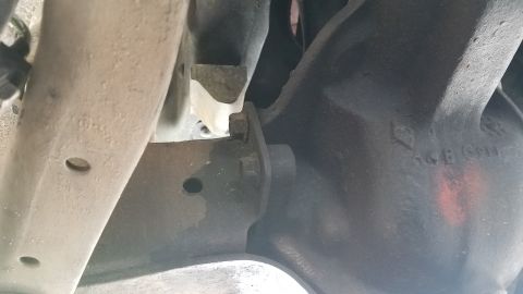 1985 Ford Bronco - A close-up view of the underside of a vehicle, showing suspension components and a bolted bracket. Visible markings on a dark metal part in…
