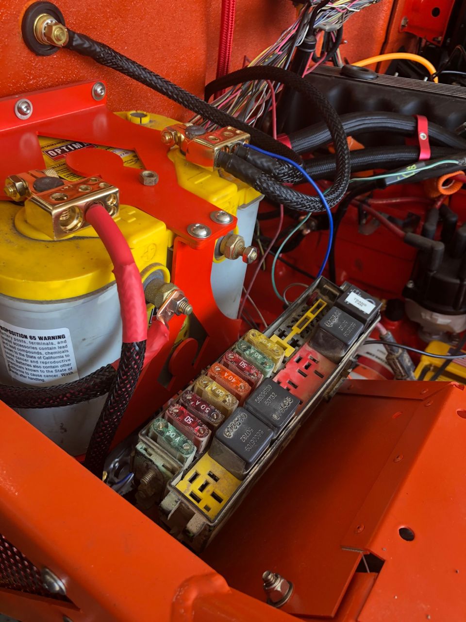 Close-up of Jeep Wrangler battery, fuse box, and wiring.