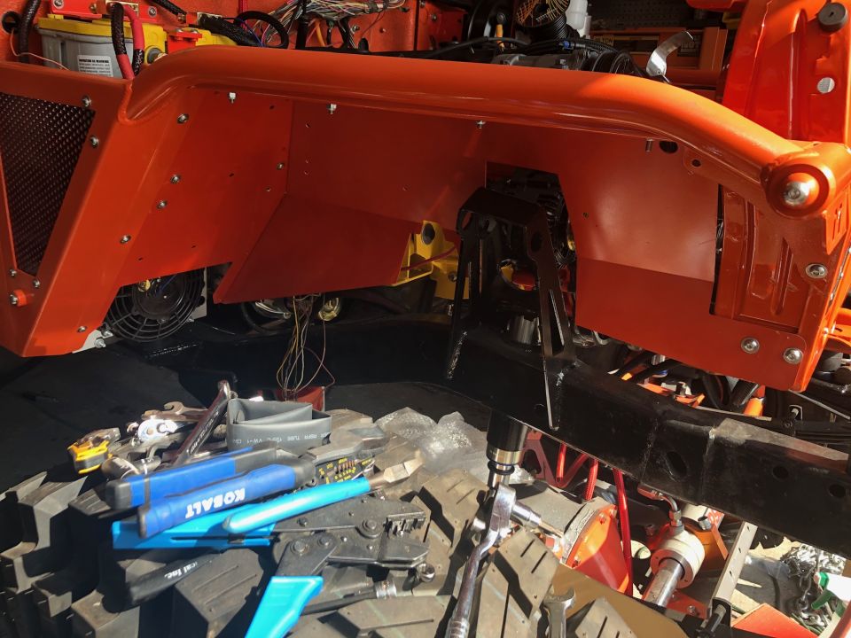 Orange Jeep Wrangler fender with rivets, black inner liner, and tools below.