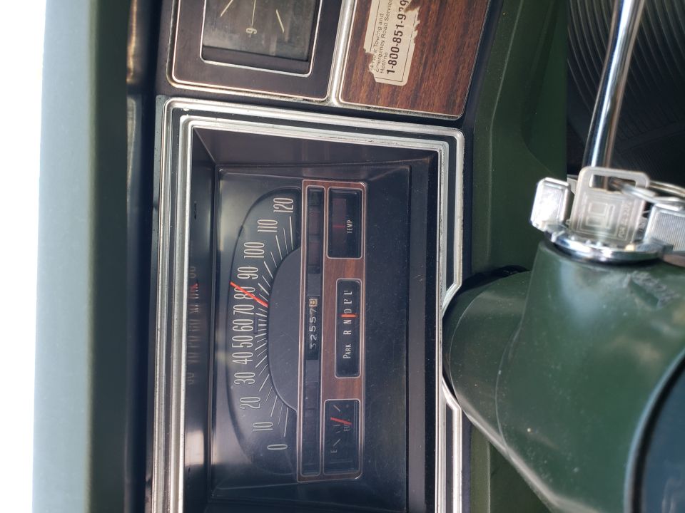 Vintage horizontal speedometer and clock in a woodgrain dash with green interior