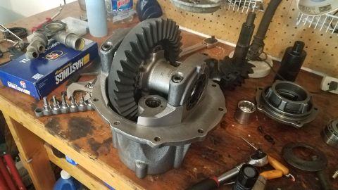 1985 Ford Bronco - A disassembled differential sits on a wooden workbench with various tools and parts scattered around it. A blue box labeled "HASTINGS Pisto…