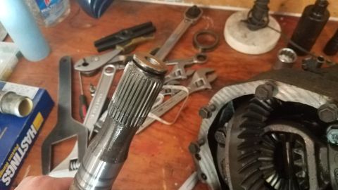 1985 Ford Bronco - A close-up view of a splined shaft and differential gears, likely from a 1985 Ford Bronco, with various tools scattered on a wooden workben…