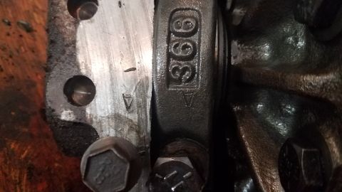 1985 Ford Bronco - A close-up view of engine components, including a connecting rod with the number "366" stamped on it, and part of a crankshaft or bearing a…