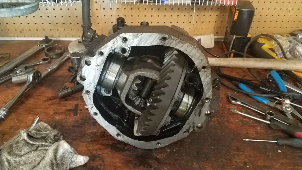 Open differential housing with gears visible, surrounded by tools on a workbench.