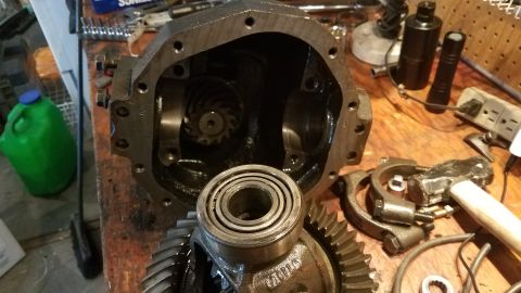 1985 Ford Bronco - A disassembled differential housing sits on a wooden workbench alongside various tools and gears. A large ring gear and a bearing are promi…