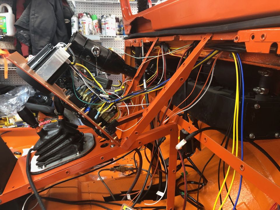 Interior of an orange Jeep Wrangler with exposed wiring harness and steering column.
