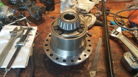 1985 Ford Bronco - A differential housing with a bearing installed sits on a wooden workbench surrounded by various tools, including wrenches, a caliper, and…
