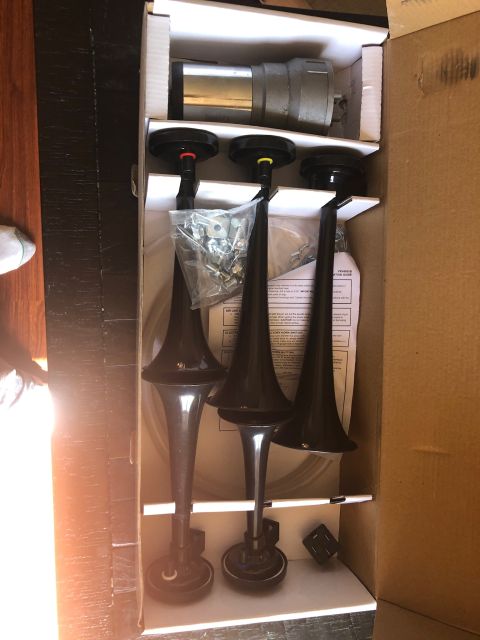 1992 Jeep Wrangler - A new set of three black air horns with red, yellow, and blue caps are laid out in a cardboard box next to a silver air compressor. The hor…
