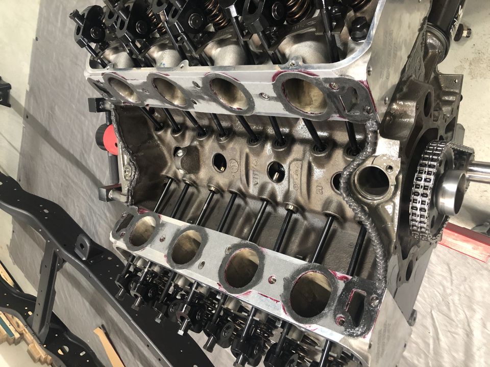 Disassembled V8 engine block with cylinder heads removed, showing intake ports and valve train.