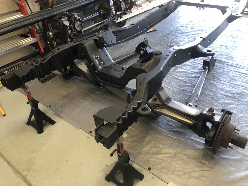 Black vehicle frame on jack stands, front suspension visible