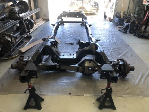 1979 Ford Bronco - A vehicle frame is supported by jack stands in a workshop, with suspension components visible.