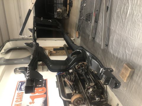 1979 Ford Bronco - Vehicle frame and suspension parts are shown, possibly for a 1979 Ford Bronco, in a workshop setting.