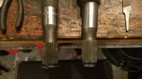 1985 Ford Bronco - Comparison of two axle shafts on a workbench, possibly for a Ford Bronco.