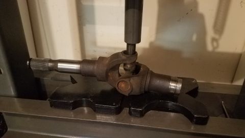 1985 Ford Bronco - A driveshaft U-joint assembly is being worked on with a press, highlighting its mechanical components.