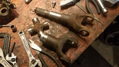1985 Ford Bronco - Driveshaft components and various tools are laid out on a wooden workbench, suggesting a repair or maintenance task.
