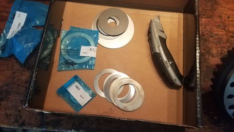 1985 Ford Bronco - Automotive shims and a utility knife are laid out in a cardboard box.