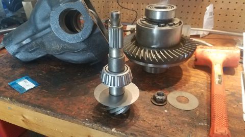 1985 Ford Bronco - Differential components, including gears and a pinion shaft, are laid out on a workbench next to a rubber mallet.