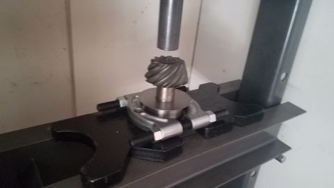 1985 Ford Bronco - A differential gear is being worked on with a specialized tool in a workshop setting.