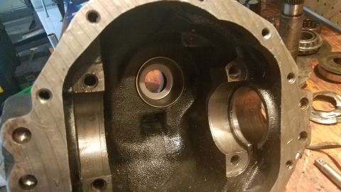 1985 Ford Bronco - Close-up of a differential housing, likely for a vehicle's drivetrain, with associated parts on a workbench.