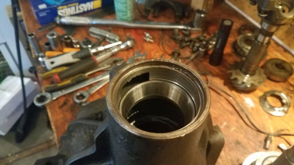 Differential housing with bearing races and assorted tools on a wooden workbench