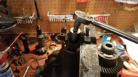 1985 Ford Bronco - Working on differential gears with a torque wrench and various tools on a cluttered workbench.