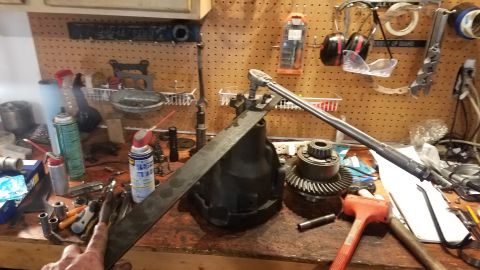 1985 Ford Bronco - A differential assembly and its gears are laid out on a workbench with various tools.